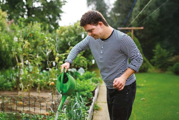 Young man watering vegetables in garden, illustrating resident wellbeing in Henley FM SIPUT II Impact Report 2025 on supported housing for vulnerable adults in UK.