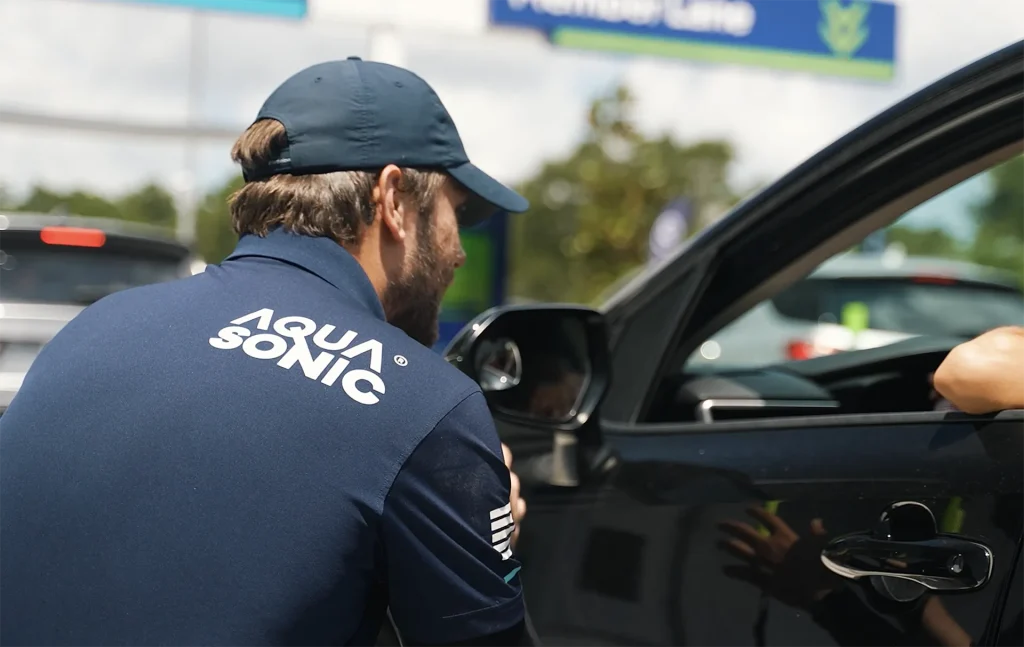 Customer-First Operations AquaSonic team member assisting a customer at the car wash entrance